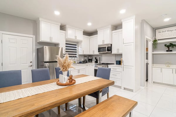 Open-plan kitchen and living room with dark wood cabinetry, stainless steel appliances, granite countertops, and brown island seating area.